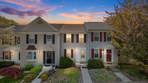 A two-story residential building with a symmetrical facade, a central entrance with a door, and a small porch area. - Asbury: Work Friendly & 40 Mins to DC (Sterling)