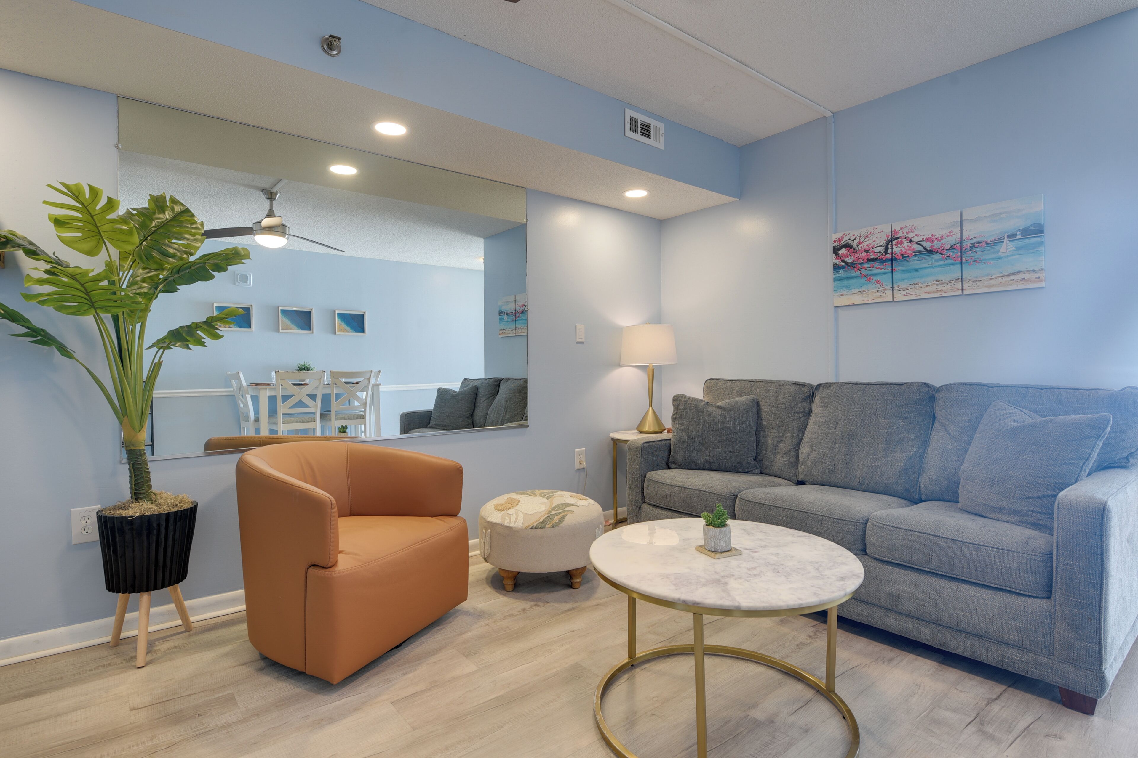 Een woonkamer met een bank, fauteuil, poef en een rond salontafeltje.