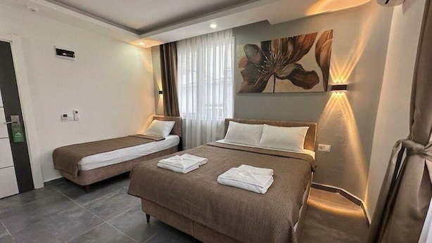Quarto de hotel com duas camas, uma grande obra de arte floral na parede e design moderno.