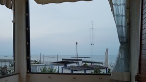 A balcony with a table and chairs, overlooking a marina with boats and a pier. - Sea view apartment with 2 bedrooms and 2 bathrooms and 1 living room (Lido di Pomposa)