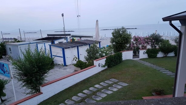 A residential area with a small house, a garage, and a garden with a stone pathway. - Sea view apartment with 2 bedrooms and 2 bathrooms and 1 living room (Lido di Pomposa)