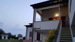 A two-story building with a balcony, a staircase, and a well-maintained lawn. - Sea view apartment with 2 bedrooms and 2 bathrooms and 1 living room (Lido di Pomposa)