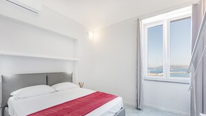 A modern bedroom with a large bed, a view of the sea, and a balcony. - Marina Grande - Gioia Apartments (Procida)