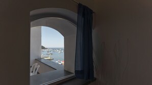 A room with a view of a marina through a window with a curtain. - Marina Grande - Gioia Apartments (Procida)
