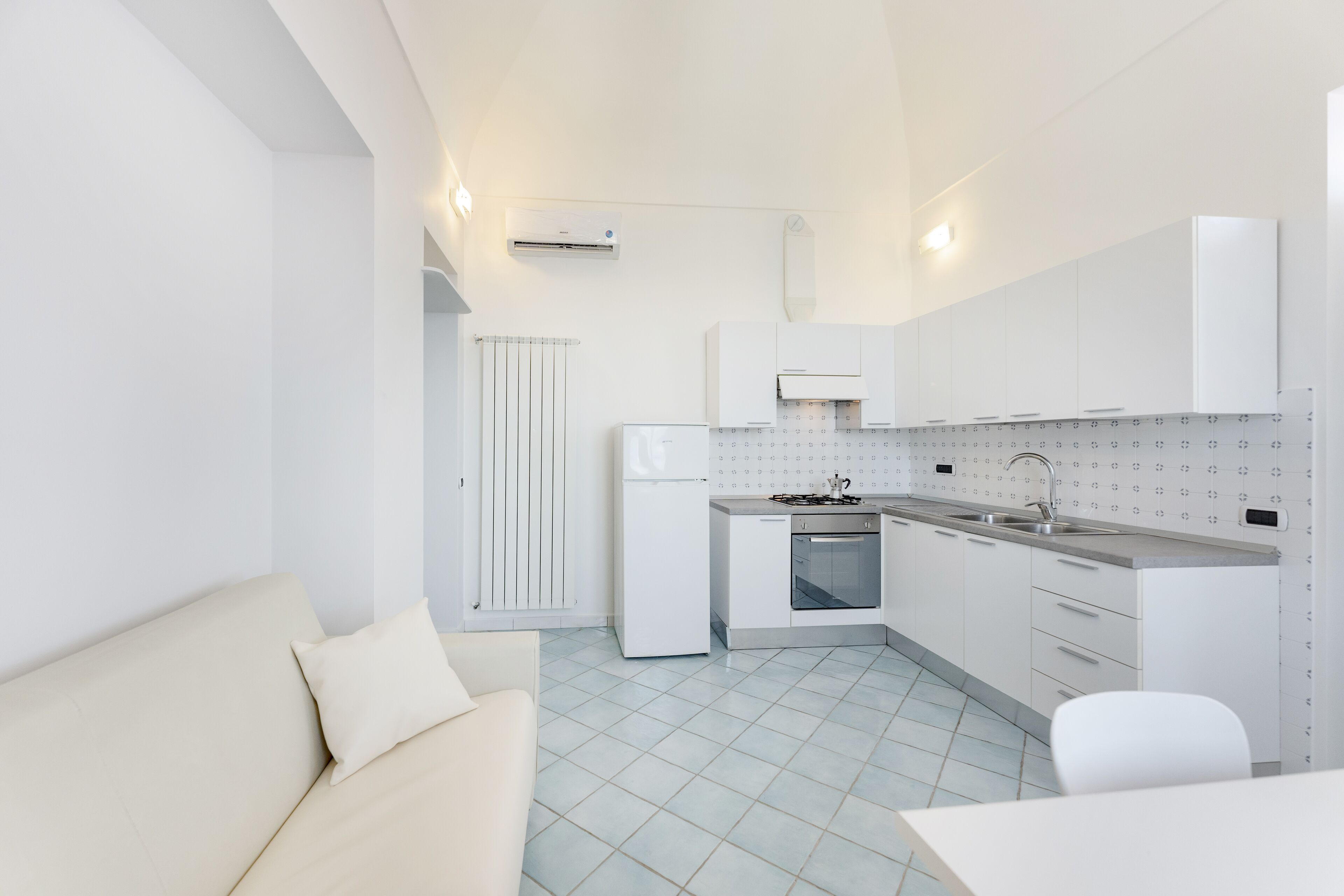 A modern kitchen with white cabinets, a refrigerator, a stove, and a sink.