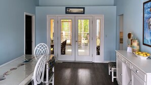 A room with a ceiling fan, a dining table with chairs, a white cabinet, and a door leading to an outdoor area. - Silver Thatch -4BR home Close to the beach. Linens and Towels Provided. (Chincoteague)