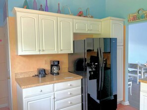 Eine Küche mit weißen Schränken, einem Kühlschrank, einer Kaffeemaschine und einem Toaster.