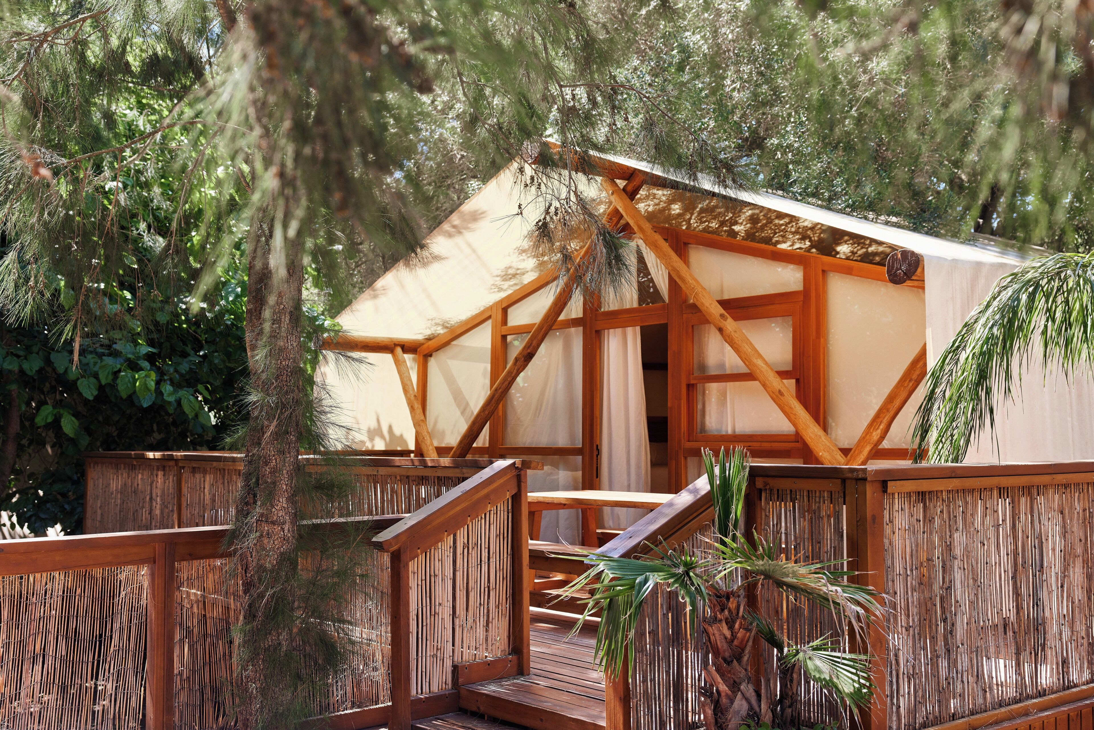 A wooden deck with a covered seating area, surrounded by dense foliage.