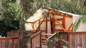 A wooden deck with a covered seating area, surrounded by dense foliage.