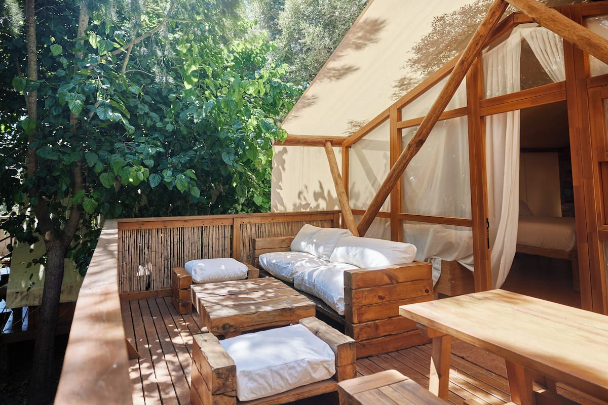 A wooden deck with a bed and a bench.