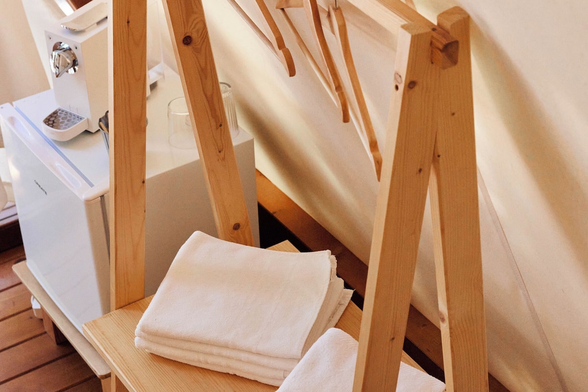 A wooden shelf with folded towels and a wooden easel in a room with wooden flooring.