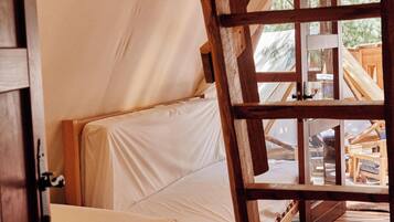 Un lit en bois avec un matelas blanc, installé dans une structure ressemblant à une tente.