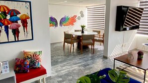 A modern living room with a dining area, a TV mounted on the wall, and a colorful artwork on the wall. - HUGE. FULL APARTMENT 100% REMODELED EXPO AREA (Zapopan)