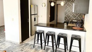 A modern kitchen with a black countertop, four bar stools, a stainless steel refrigerator, and pendant lights. - HUGE. FULL APARTMENT 100% REMODELED EXPO AREA (Zapopan)