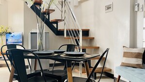 Een eetruimte met een ronde tafel, zwarte stoelen en een trap met een afbeelding van palmbomen.