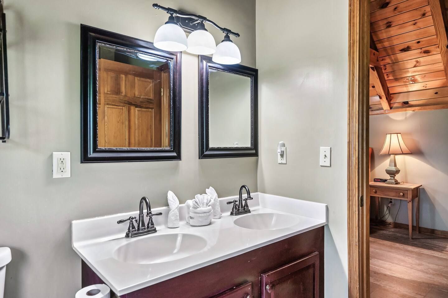 A bathroom with two sinks, a large mirror, and a wooden ceiling.