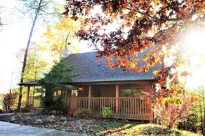 A single-story house with a porch, surrounded by autumn foliage.