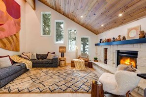 Un salon chaleureux avec une cheminée, de grandes fenêtres et un ensemble de meubles modernes, dont un canapé.