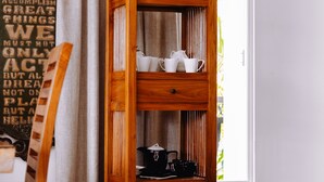A wooden bookshelf with shelves containing various items, positioned near a window with curtains. - south hill villa (Mahe)