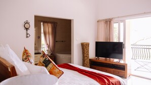 A bedroom with a bed, a television, a wooden cabinet, a bathroom with a shower curtain, and a balcony with a railing. - south hill villa (Mahe)