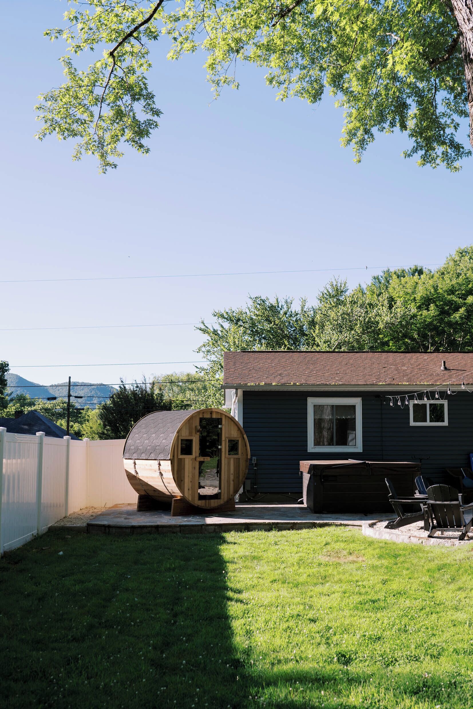 A wooden barrel structure in a backyard with a house in the background.