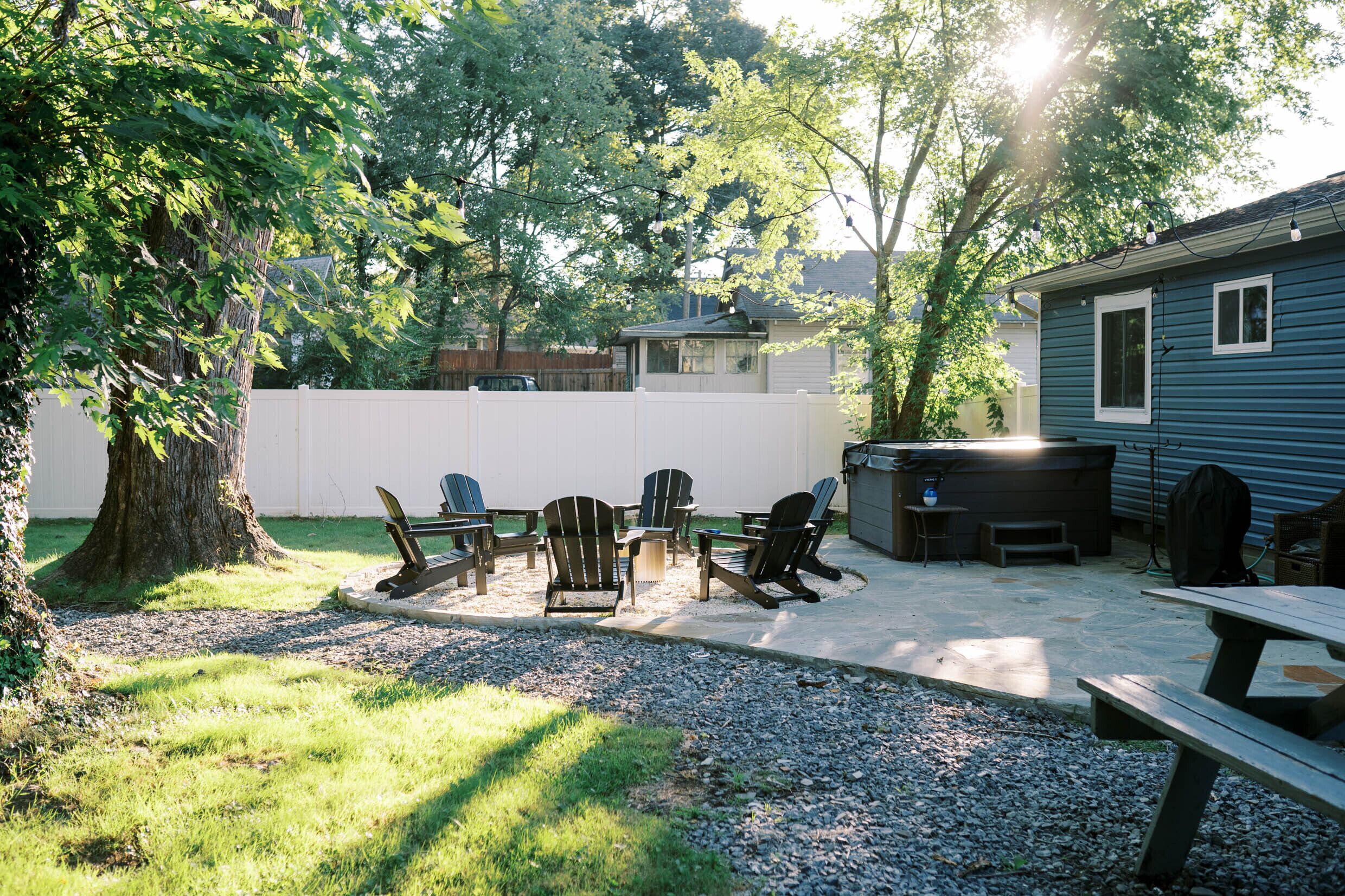 A backyard with a barbecue grill, picnic table, and Adirondack chairs.
