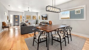 Ein modernes Wohnzimmer mit einem Holzesstisch, dunklen Stühlen und einem grauen Sofa.
