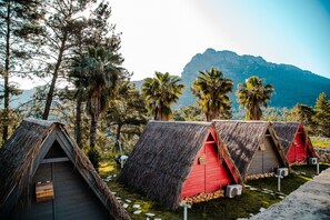 Cabañas con techo de paja en fila, con montañas al fondo.