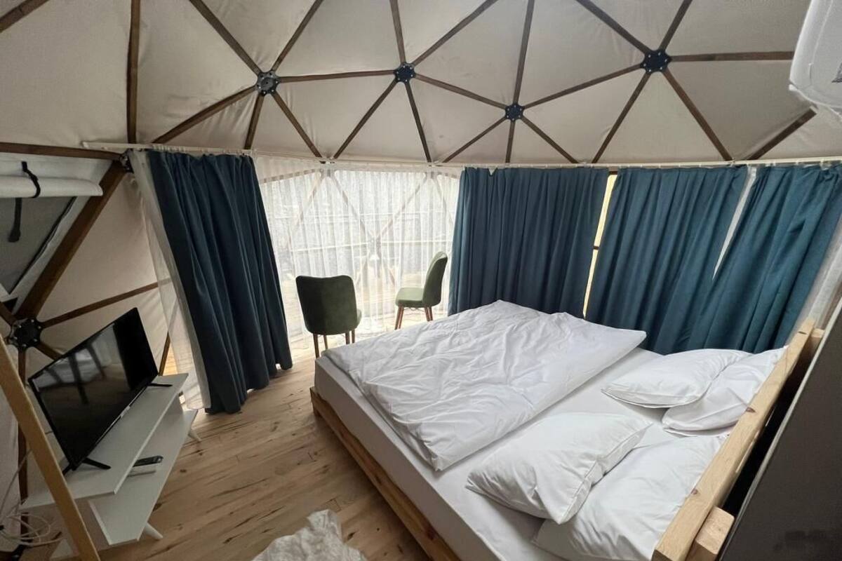 Ein Zeltraum mit einem Bett, einem Schreibtisch mit Computer und einem Stuhl.