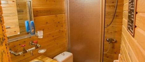 Baño de cabaña de madera con lavamanos, inodoro y ducha.