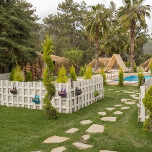 Un patio trasero con piscina, palmeras y una cerca blanca con jardineras colgantes.