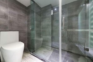 Une salle de bain avec une douche à parois de verre, des toilettes et des murs carrelés.