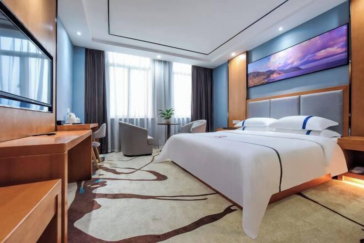 Une chambre d’hôtel moderne équipée d’un grand lit, d’un bureau, d’une chaise et d’un téléviseur.