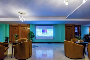Un salón de conferencias con una pantalla grande, puertas de madera y asientos.