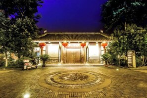 A traditional building with a tiled roof, a central entrance, and a circular stone pattern in the foreground. - Chongqing Jinfeng Hotel (Chongqing)