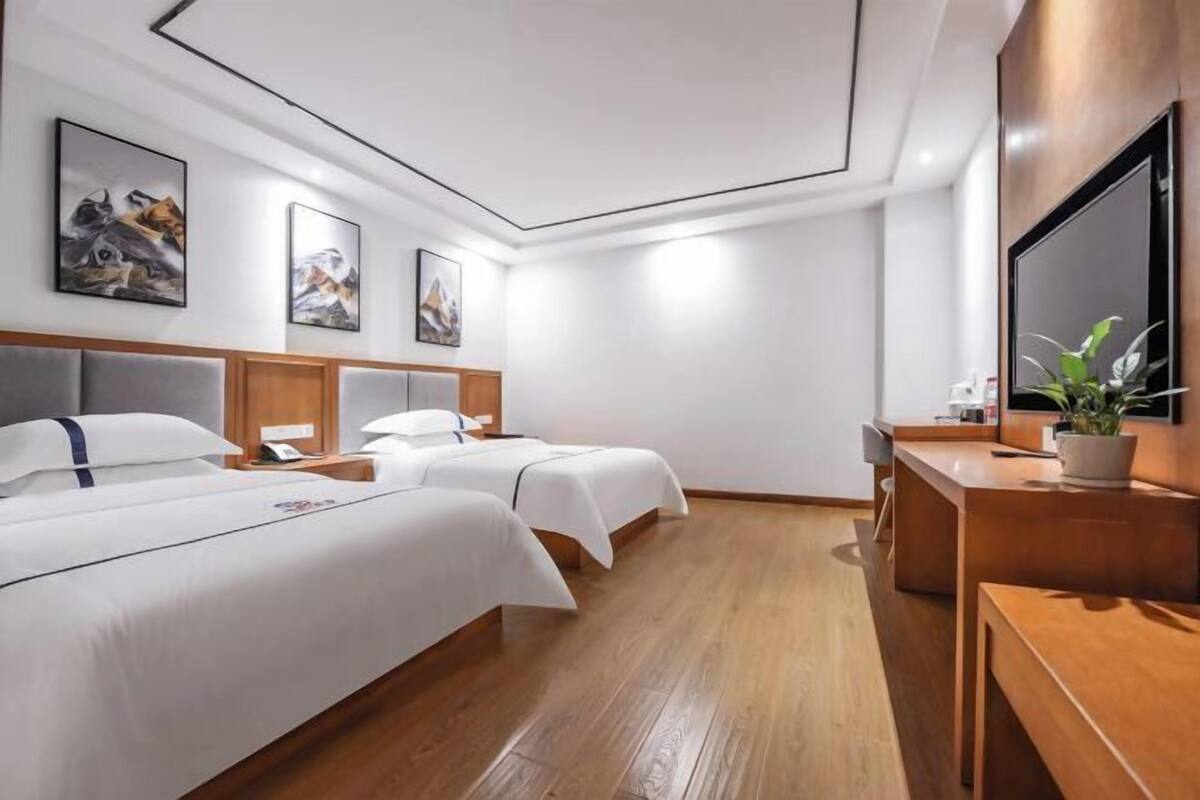 Une chambre d’hôtel avec deux lits, un bureau, une chaise et un téléviseur.