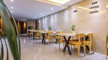 A hotel lobby with a long reception desk, several tables and chairs, and a polished floor.