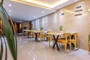 Un vestíbulo de hotel con una larga recepción, varias mesas y sillas, y un piso pulido.