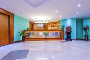 A hotel reception area with a wooden reception desk, a potted plant, and a reception counter. - Chongqing Jinfeng Hotel (Chongqing)
