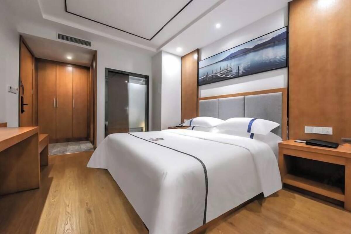 Une chambre d’hôtel moderne avec un grand lit, un bureau et un tableau au mur.