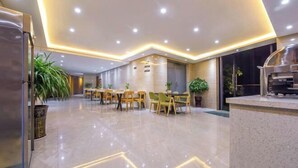A modern hotel lobby with a central seating area, a reception desk, and a large window.