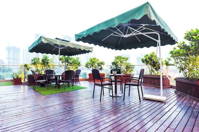 An outdoor seating area with tables and chairs, umbrellas, and potted plants.