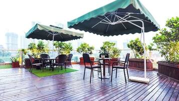 An outdoor seating area with tables and chairs, umbrellas, and potted plants.