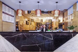 A hotel reception area with a marble counter, hanging lamps, and a receptionist. - Chongqing Jinfeng Hotel (Chongqing)