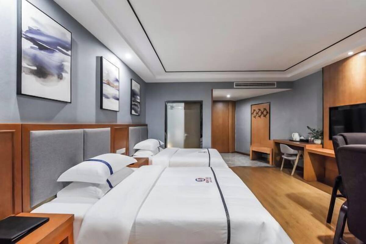 Une chambre d’hôtel avec un lit, un bureau, une chaise et des œuvres d’art accrochées aux murs.
