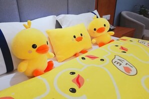 Uma cama com três brinquedos de pato amarelos e um travesseiro com estampa de rosto de pato.