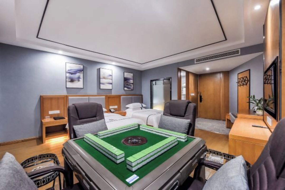 Habitación de hotel con cama, dos sillones, escritorio y mesa de billar.
