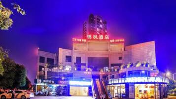 A hotel with a prominent sign, a covered entrance, and an adjacent building with illuminated signage.