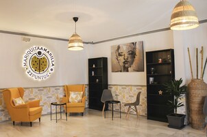 Un vestíbulo con dos sillones amarillos, una estantería negra y un letrero grande en la pared.