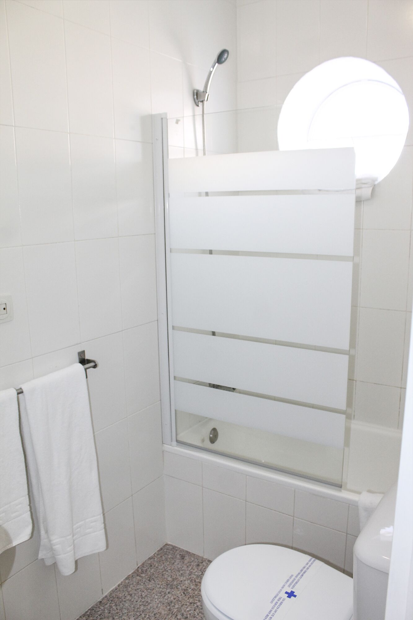 Een badkamer met een douchecabine van glas, een toilet en een handdoekhouder.